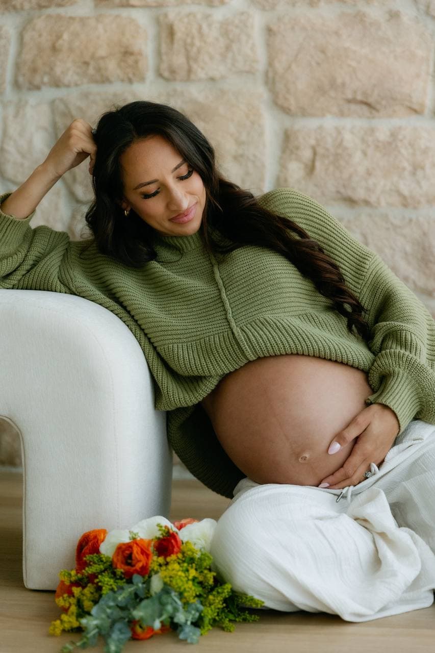 Portrait of an expectant mother seated beside flowers